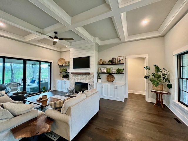 living room featuring ceiling fan, dark hardwood / wood-style flooring, coffered ceiling, and a brick fireplace