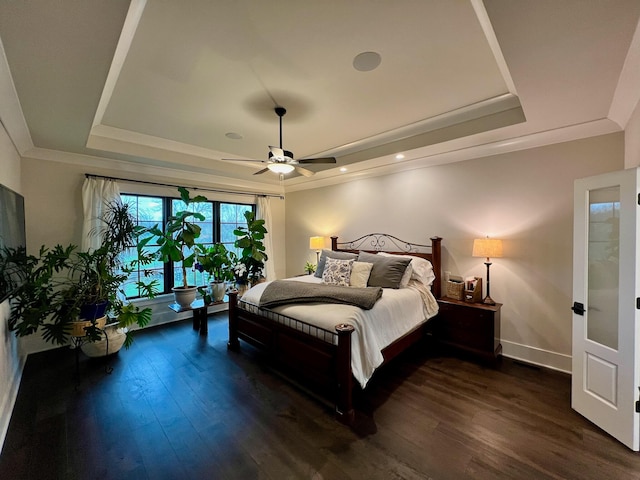 bedroom featuring ceiling fan, dark hardwood / wood-style flooring, and a tray ceiling