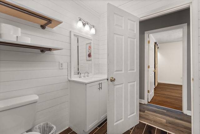 bathroom featuring vanity, hardwood / wood-style flooring, toilet, and wooden walls