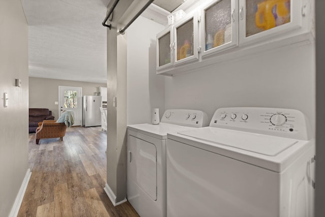 clothes washing area with washer and dryer and wood-type flooring