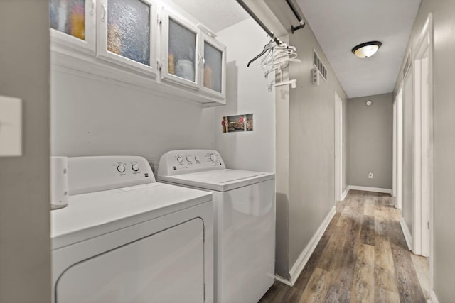 laundry room with separate washer and dryer and wood-type flooring