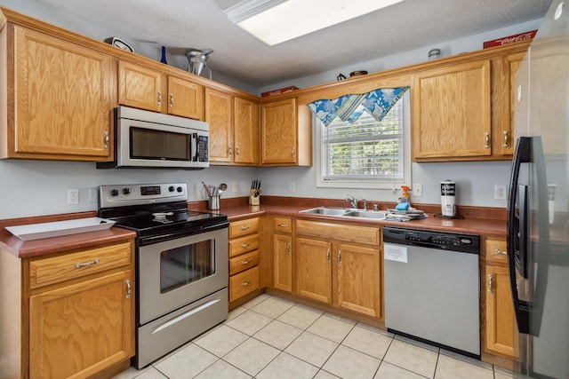 kitchen with light tile patterned flooring, appliances with stainless steel finishes, a textured ceiling, and sink