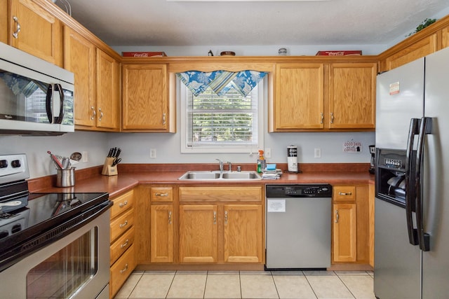 kitchen with a textured ceiling, sink, light tile patterned floors, and stainless steel appliances