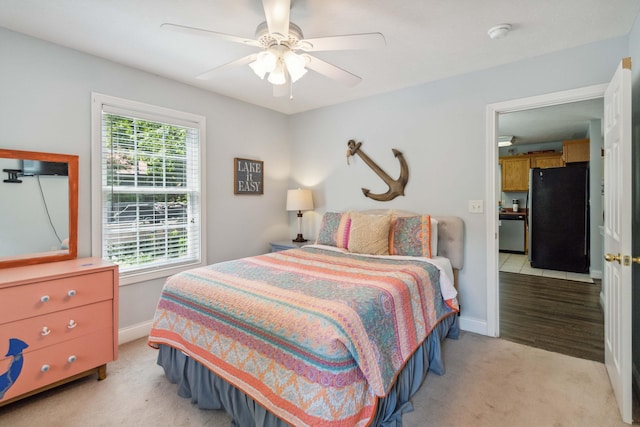 carpeted bedroom with ceiling fan and black refrigerator