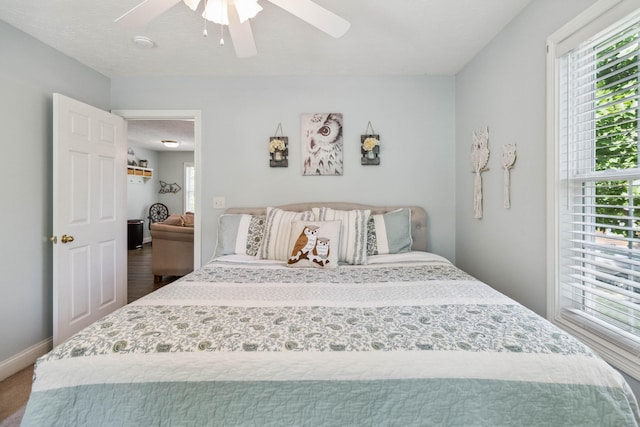 bedroom with hardwood / wood-style floors, ceiling fan, and a textured ceiling