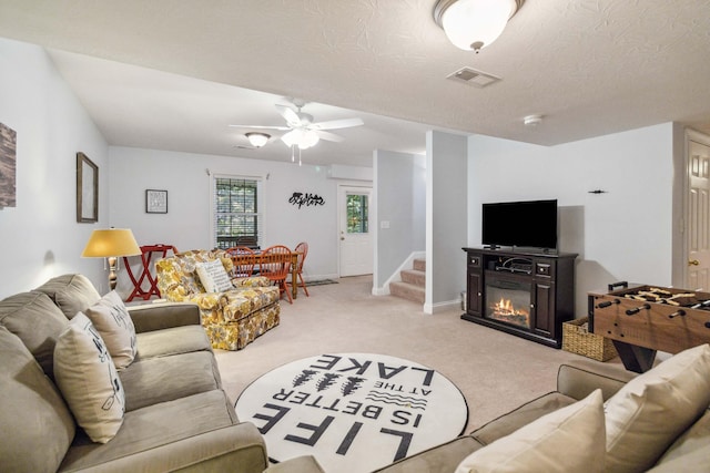 carpeted living room with ceiling fan and a textured ceiling