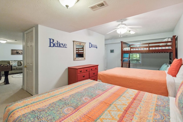 carpeted bedroom with ceiling fan and a textured ceiling