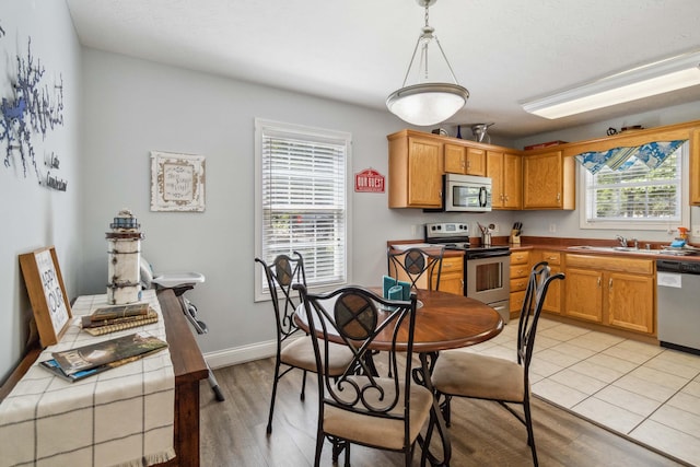 kitchen with tile countertops, hanging light fixtures, stainless steel appliances, and light hardwood / wood-style floors