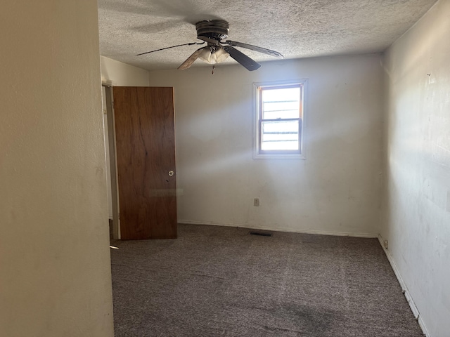 unfurnished room featuring ceiling fan, dark carpet, and a textured ceiling