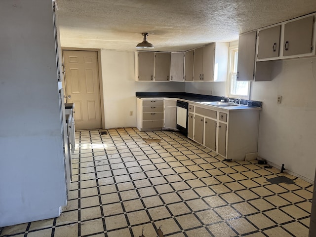 kitchen with a textured ceiling, dishwasher, and sink