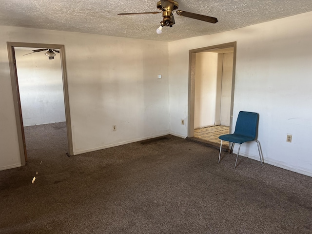 empty room featuring ceiling fan, dark carpet, and a textured ceiling