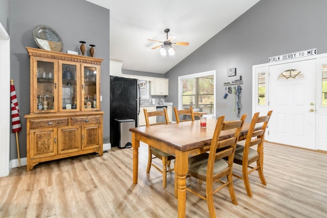 dining room with ceiling fan, high vaulted ceiling, and light hardwood / wood-style flooring