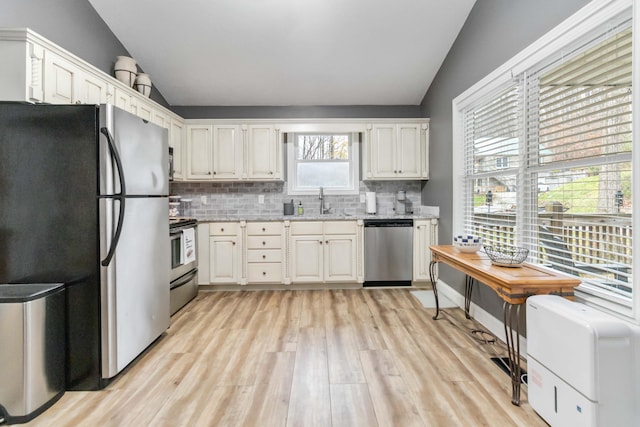 kitchen with plenty of natural light, light hardwood / wood-style floors, lofted ceiling, and stainless steel appliances