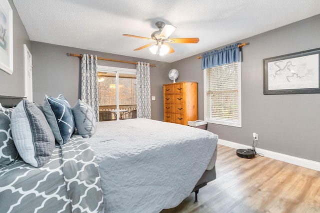 bedroom featuring access to outside, a textured ceiling, hardwood / wood-style flooring, and ceiling fan