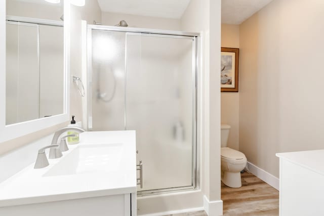 bathroom featuring toilet, vanity, a shower with shower door, and hardwood / wood-style flooring