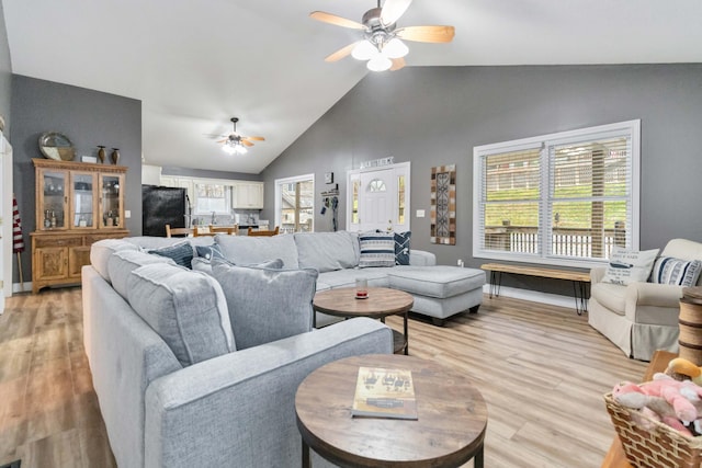 living room featuring ceiling fan, lofted ceiling, and light hardwood / wood-style flooring