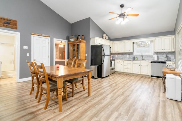 dining space featuring ceiling fan, sink, high vaulted ceiling, and light hardwood / wood-style flooring