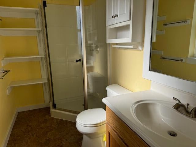 bathroom featuring toilet, vanity, and walk in shower