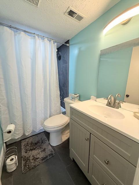 bathroom with tile patterned flooring, vanity, a textured ceiling, and toilet