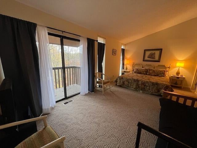 carpeted bedroom with access to exterior and vaulted ceiling