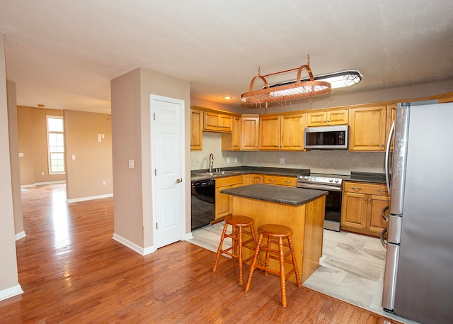 kitchen featuring stainless steel appliances, a breakfast bar, tasteful backsplash, a kitchen island, and sink