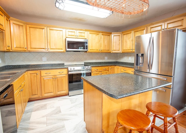 kitchen featuring a center island, stainless steel appliances, tasteful backsplash, a breakfast bar area, and sink