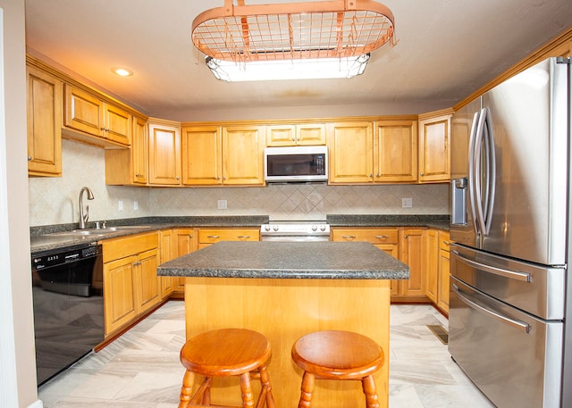 kitchen featuring a breakfast bar area, appliances with stainless steel finishes, a kitchen island, sink, and tasteful backsplash