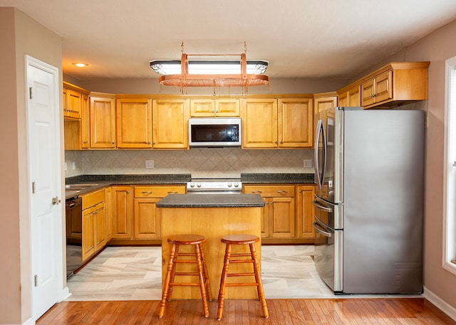 kitchen featuring a kitchen breakfast bar, decorative backsplash, a center island, and appliances with stainless steel finishes