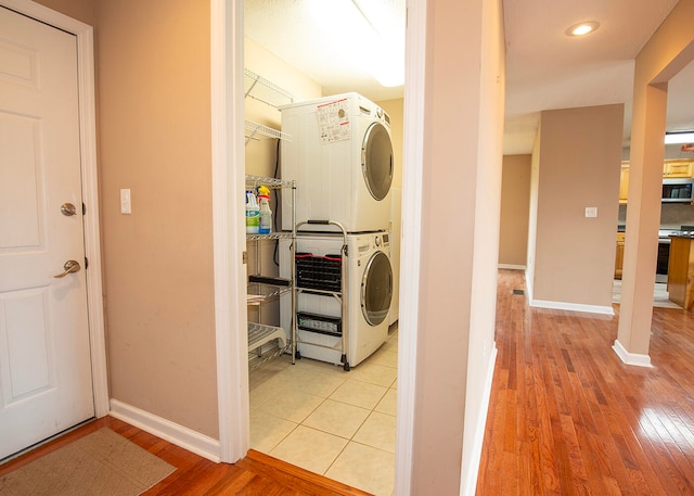 clothes washing area with stacked washing maching and dryer and light hardwood / wood-style flooring