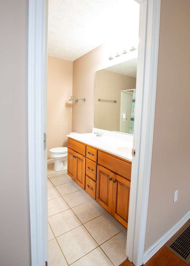 bathroom featuring toilet, tile patterned flooring, a textured ceiling, and vanity