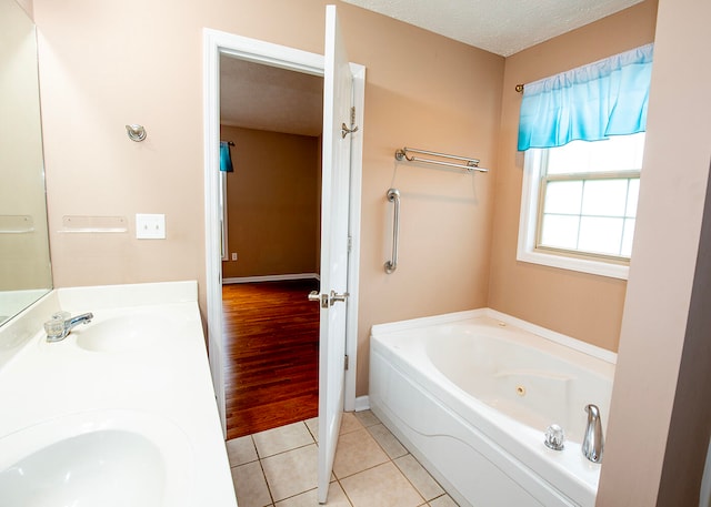 bathroom featuring a textured ceiling, a bath, vanity, and tile patterned floors