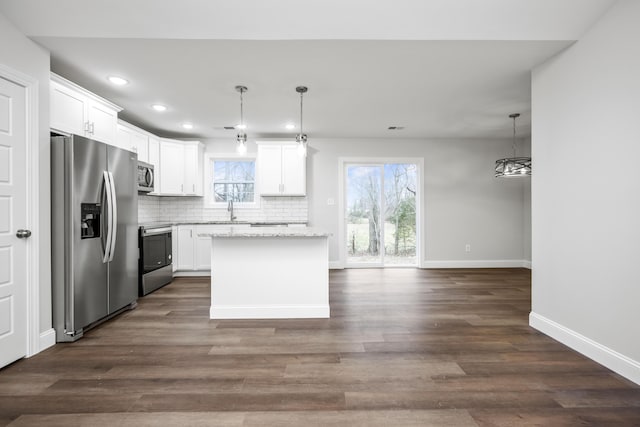 kitchen featuring decorative backsplash, appliances with stainless steel finishes, dark wood-type flooring, a sink, and a kitchen island