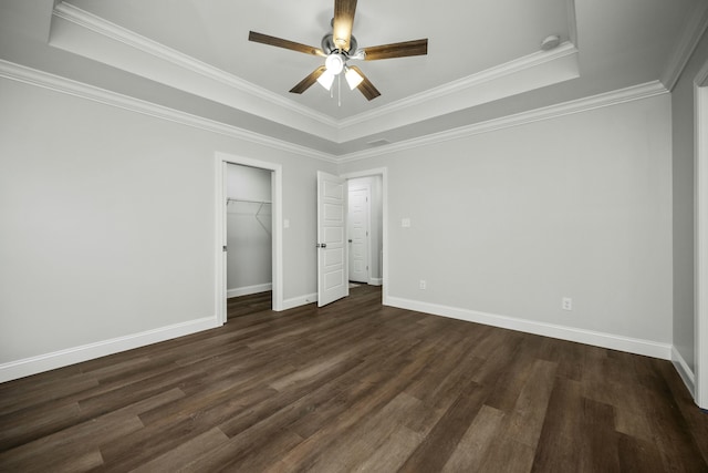 unfurnished bedroom featuring ornamental molding, a raised ceiling, dark wood finished floors, and baseboards