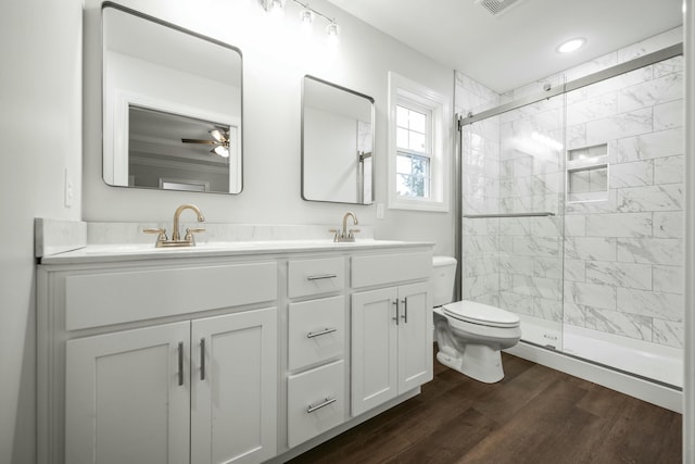 bathroom featuring hardwood / wood-style floors, toilet, vanity, ceiling fan, and an enclosed shower