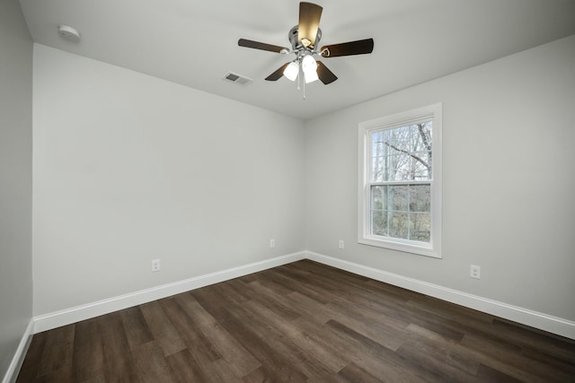 spare room featuring baseboards, visible vents, ceiling fan, and dark wood-type flooring