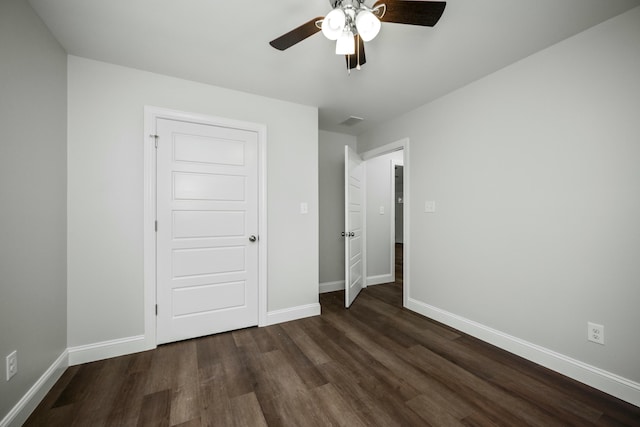 unfurnished bedroom featuring dark wood-style floors, visible vents, baseboards, and a ceiling fan