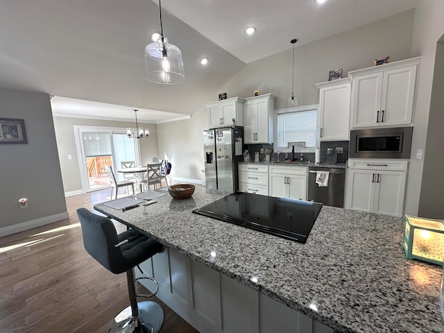 kitchen featuring white cabinetry, light stone countertops, hanging light fixtures, stainless steel appliances, and a chandelier