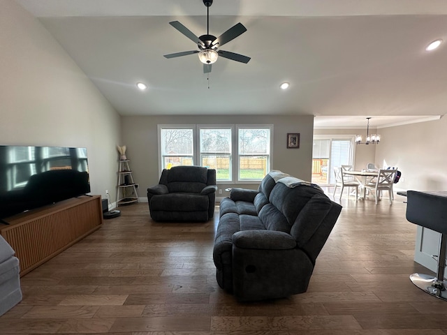 living room featuring ceiling fan with notable chandelier, dark wood-type flooring, and vaulted ceiling