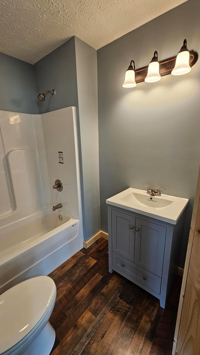 full bathroom featuring hardwood / wood-style floors, vanity, toilet, a textured ceiling, and tub / shower combination