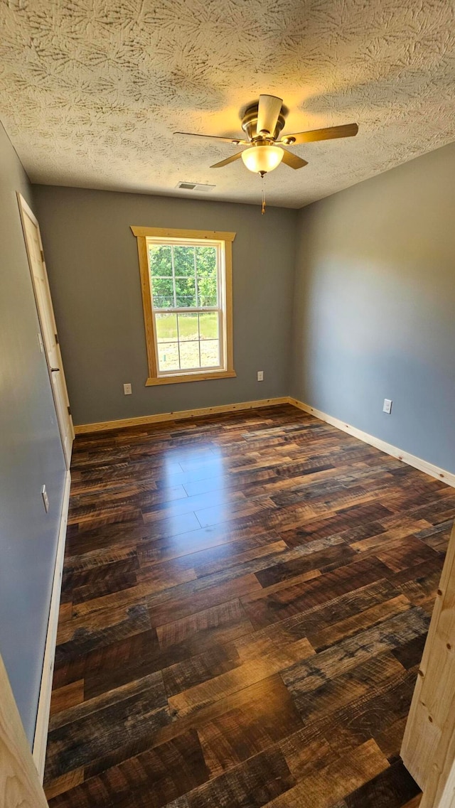 spare room with a textured ceiling, ceiling fan, and dark hardwood / wood-style floors