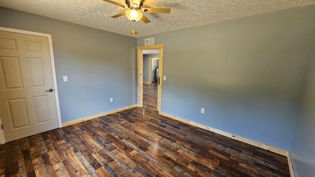 empty room featuring a textured ceiling, dark hardwood / wood-style flooring, and ceiling fan