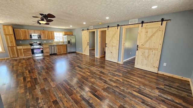 kitchen with ceiling fan, dark hardwood / wood-style flooring, a textured ceiling, and appliances with stainless steel finishes