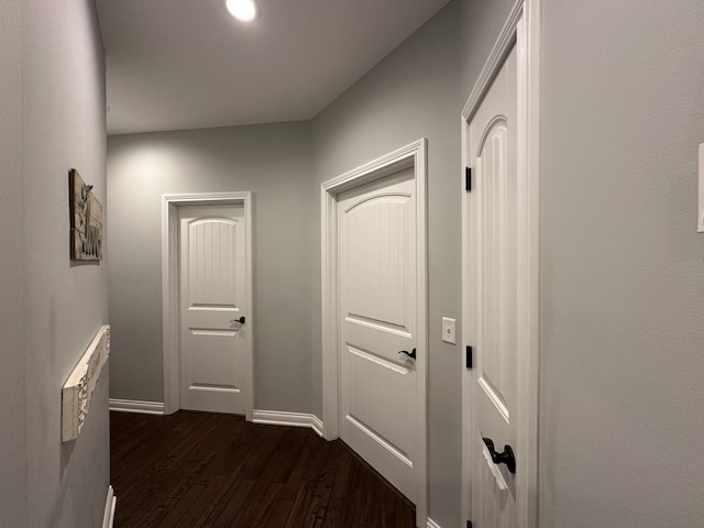 hallway featuring dark wood-type flooring and baseboards