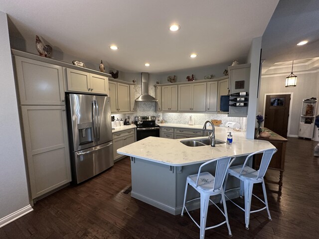 kitchen featuring black range with electric stovetop, a sink, stainless steel fridge, a peninsula, and wall chimney range hood