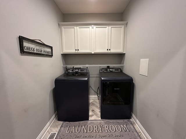 laundry area with washing machine and clothes dryer, visible vents, cabinet space, and baseboards