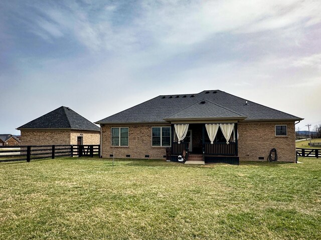 rear view of property with a yard, fence, brick siding, and crawl space