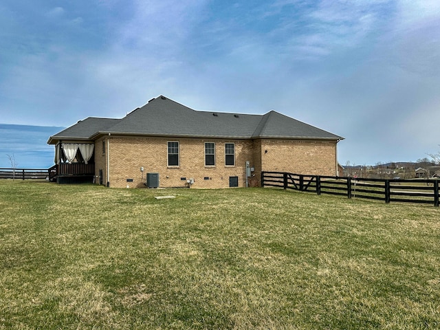 rear view of house with fence, crawl space, central air condition unit, a lawn, and brick siding