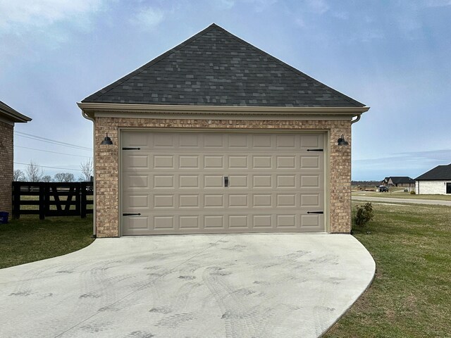 garage featuring concrete driveway and fence