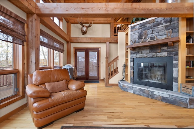 living room featuring a stone fireplace, wood finished floors, baseboards, french doors, and stairway