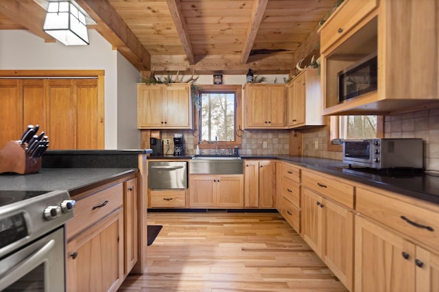 kitchen with appliances with stainless steel finishes, beam ceiling, decorative backsplash, light wood finished floors, and dark countertops